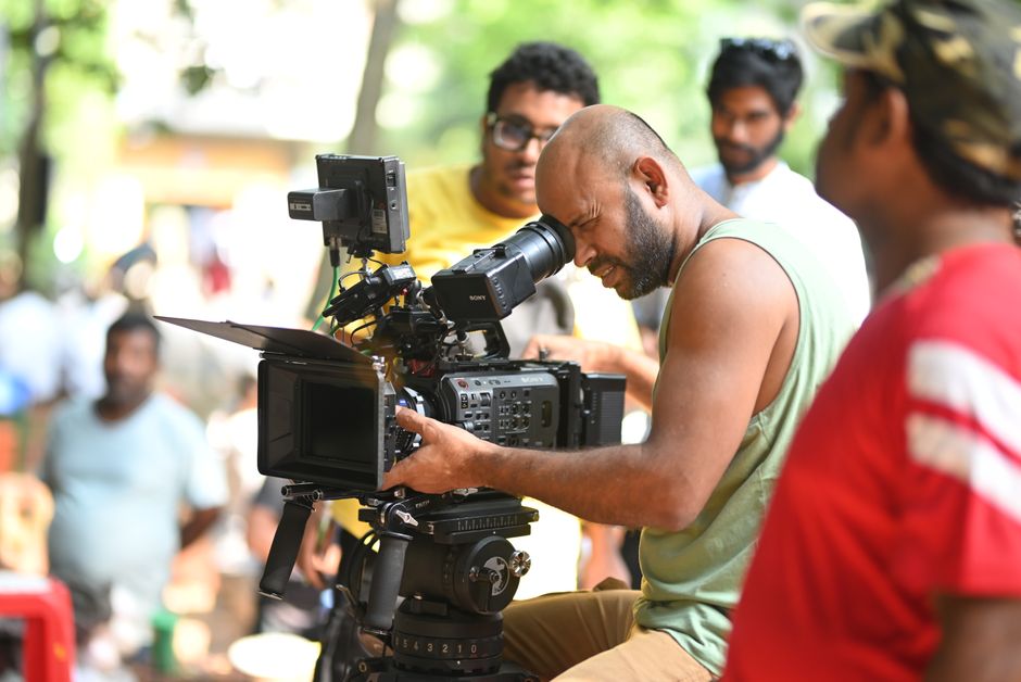 Cultura Brasileira — Filmmaker using a professional video camera on an outdoor set, surrounded by crew members.