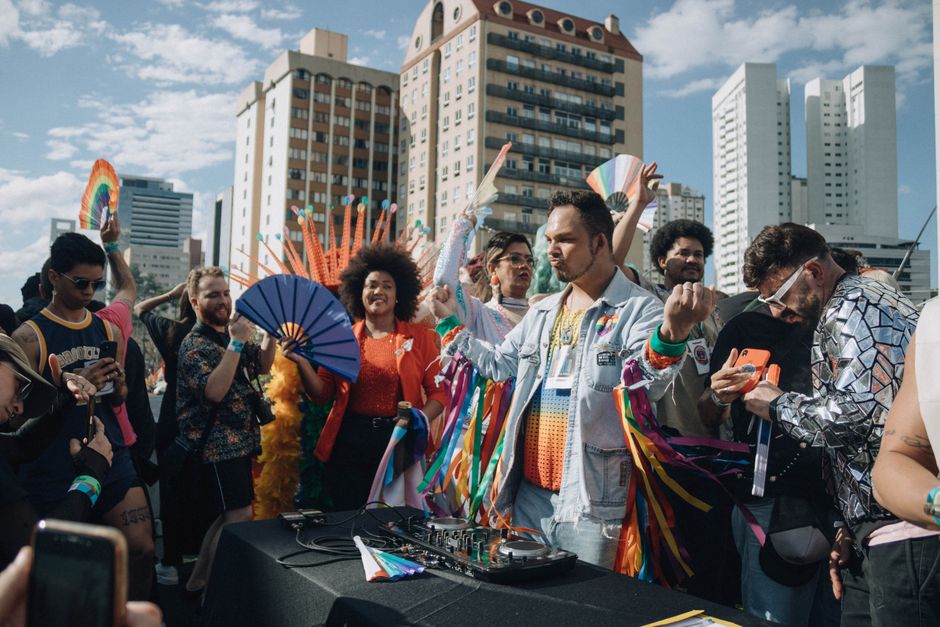 Cultura Brasileira — Lively LGBTQ+ parade with diverse crowd enjoying music in an urban backdrop.